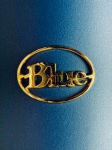 Close-up of the golden 'Blue' brand logo on a blue background, showcasing the polished finish and elegant design of the emblem.