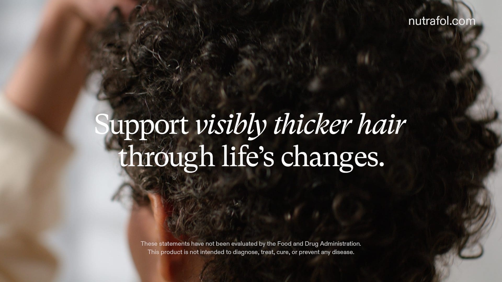 Close-up image of the back of a person's head with curly hair, with text overlay stating 'Support visibly thicker hair through life’s changes' along with the Nutrafol logo and website address nutrafol.com, emphasizing hair wellness.