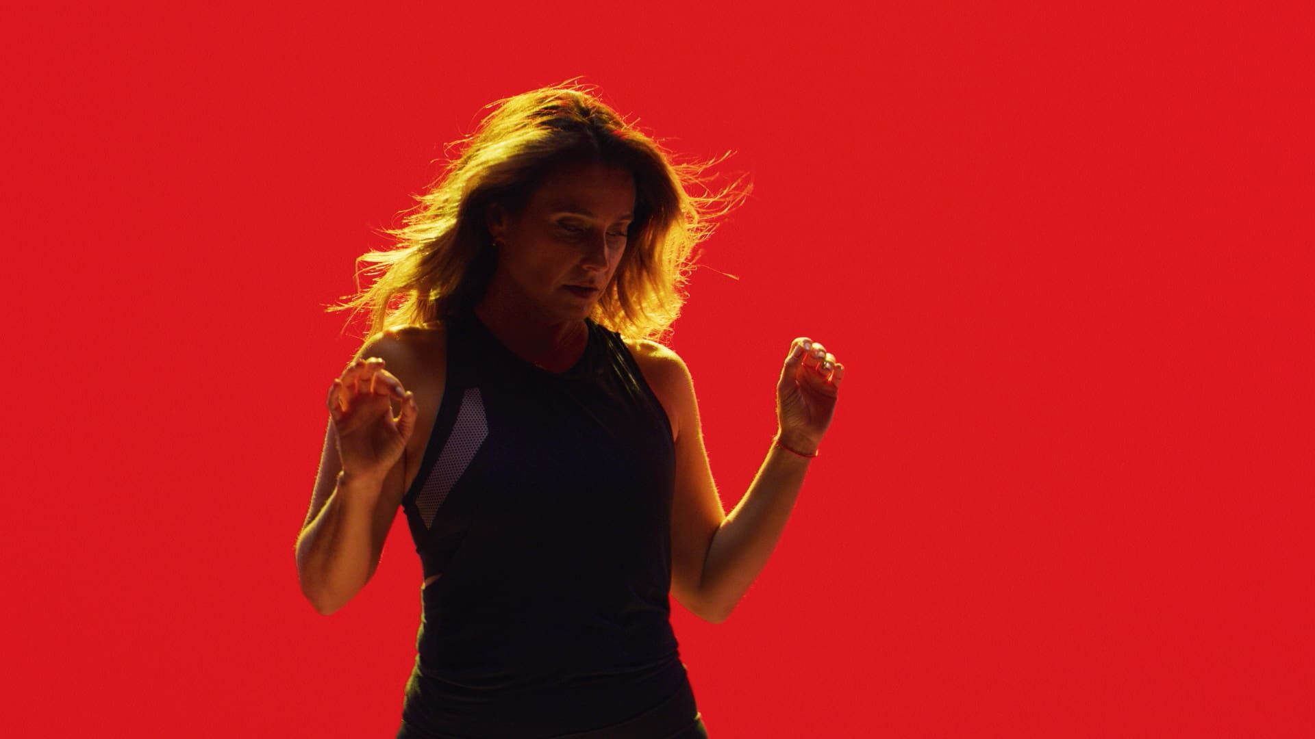 Laurie Cole captured mid-motion against a bold red backdrop, embodying strength, rhythm, and resilience during the SoulCycle docufilm series.