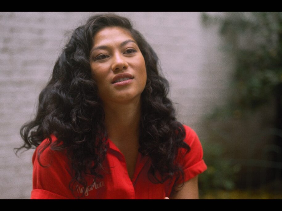 Portrait of Soureya, SoulCycle instructor, in contemplative moment, wearing a red outfit indicative of her dynamic energy, captured in New York City for the SoulCycle Docufilm
