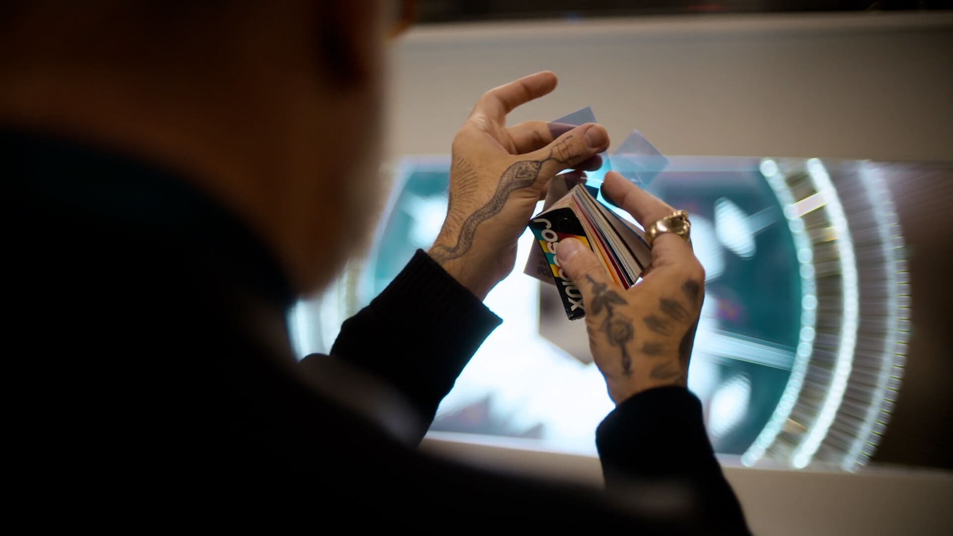 Artisan's hands with tattoos carefully selecting colorful light filters for Tiffany & Co.'s holiday window display.