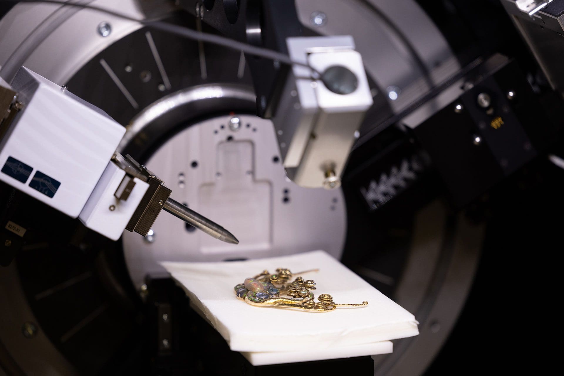 High-precision jewelry crafting equipment with a piece of intricate gold jewelry placed on a white cloth, depicting the modern technology used in fine jewelry making at Tiffany & Co.