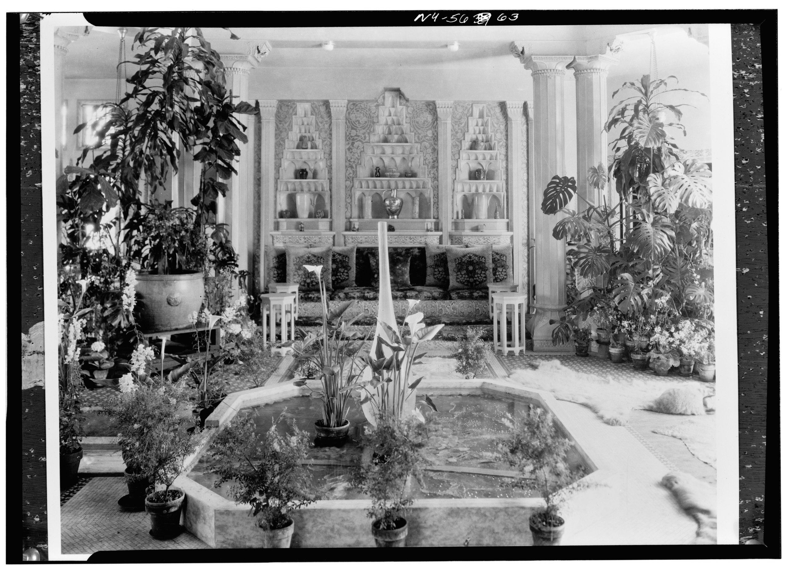 The Central Court at Laurelton Hall, featuring a marble fountain, lush greenery, and Tiffany vases in architectural niches. Photo by David Aronow, via Wikimedia Commons.