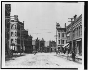 A historical photograph of Front Street, Missoula, Montana, from the early 1900s, showing buildings, carriages, and pedestrians.