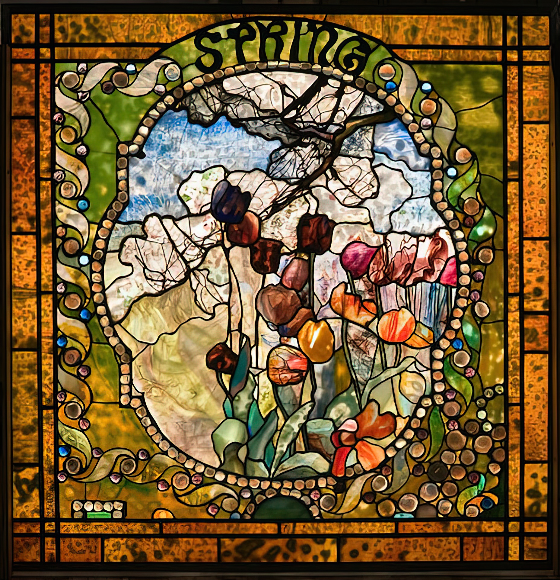 “Spring” panel from Tiffany Studios’ Four Seasons stained glass window, depicting vibrant flowers and swirling motifs. Image via Wikimedia Commons.