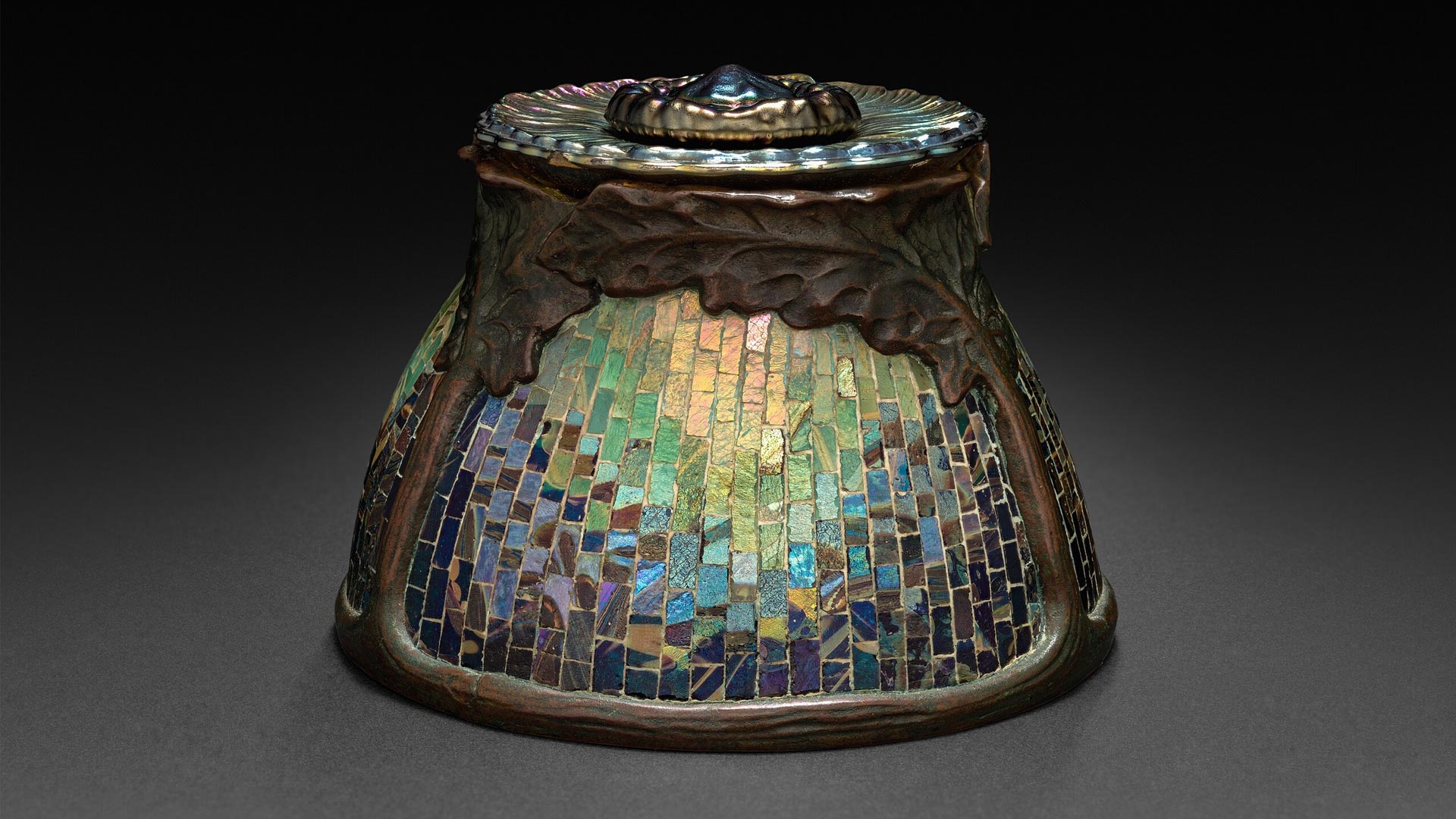 Tiffany Studios inkwell designed by Clara Wolcott Driscoll, featuring iridescent mosaic glass and bronze oak leaves. Image via Wikimedia Commons.